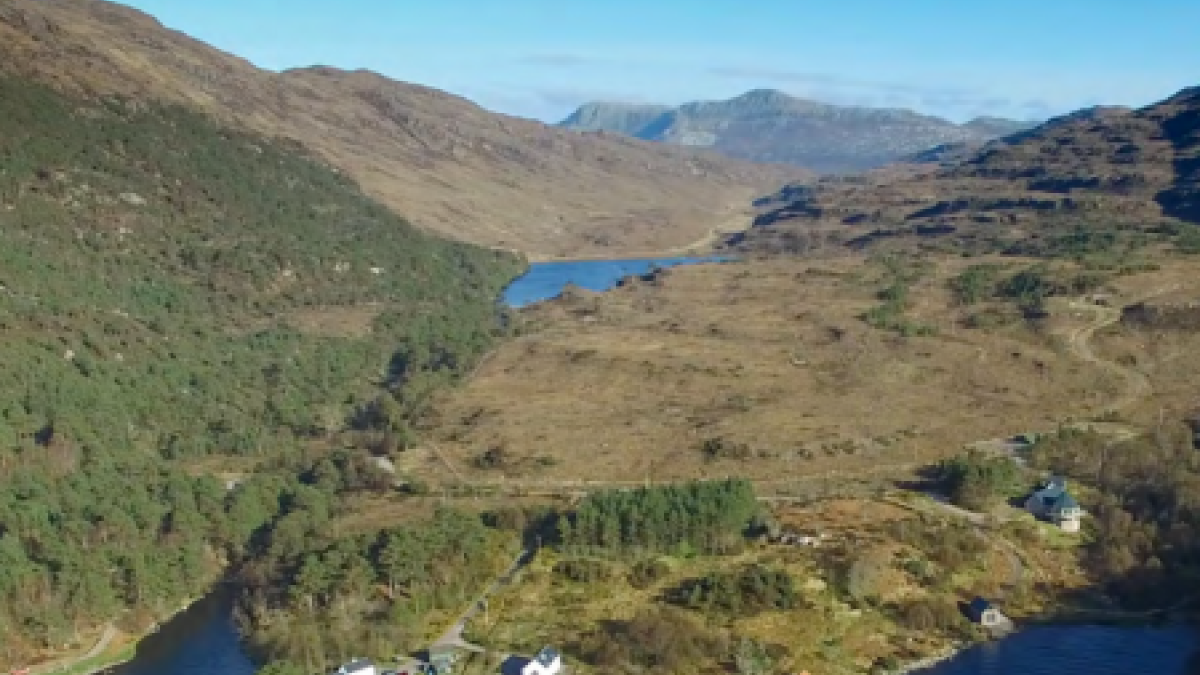 Aerial view of Kinloch Woodland, showing a body of water, hills and blue sky