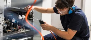Person wearing goggles and ear defenders remanufacturing printer