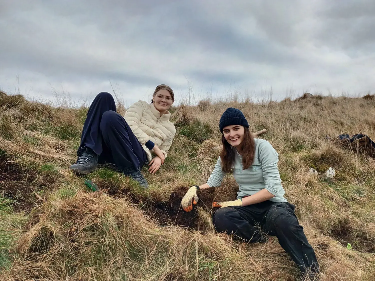 two people sitting on a grassy hillside