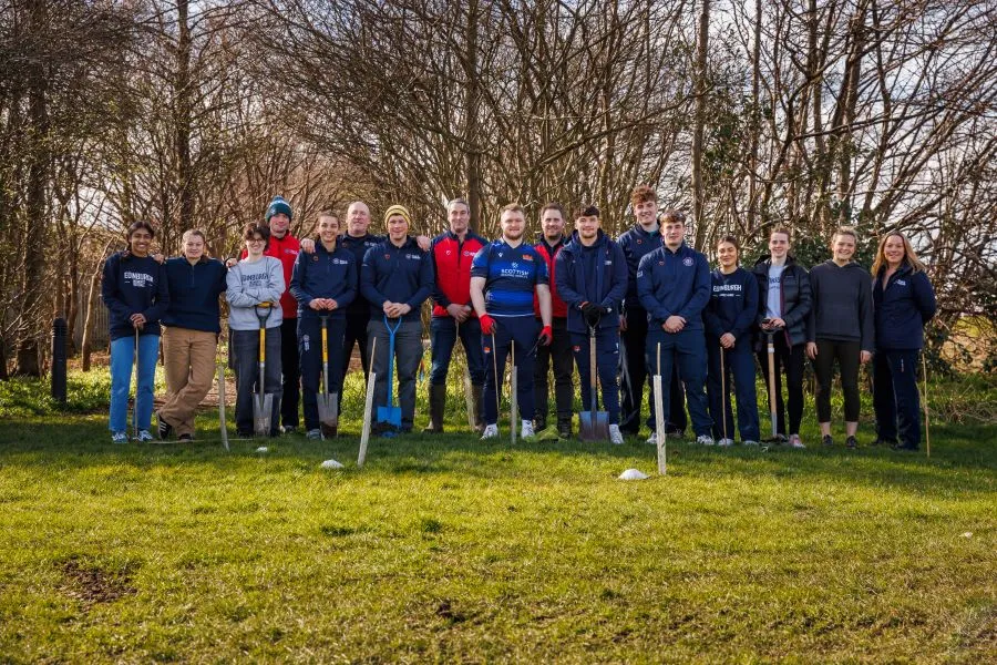 A group photo of about 20 student athletes assembled outside at Peffermill Playing Fields.