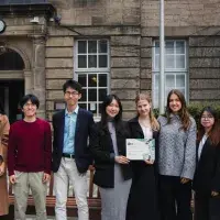 Changemakers hold certificate in courtyard