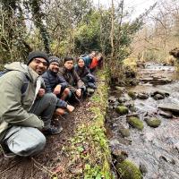 Edinburgh Hikers student society crouched beside a burn in nature