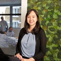 A photo of a woman smiling against a green background in an office