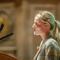 A person stands at a lecturn, speaking