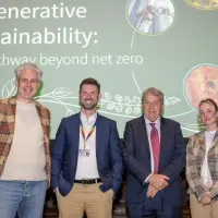 four people stand on a stage with a slide behind them that reads "Regenerative sustainability: our pathway beyond net zero"