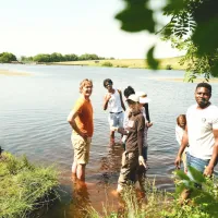 A group of people enjoy standing in water on a sunny day.
