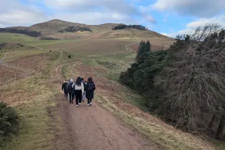Students in the distance walking along a path with hills on either side.