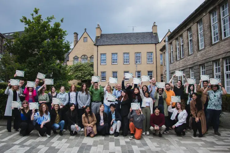 Changemakers hold certificates in courtyard