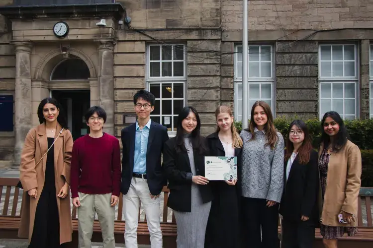 Changemakers hold certificate in courtyard