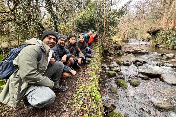 Edinburgh Hikers student society crouched beside a burn in nature