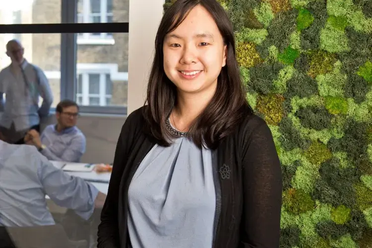 A photo of a woman smiling against a green background in an office