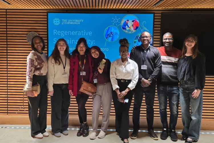 A group of people stand in front of a screen, smiling