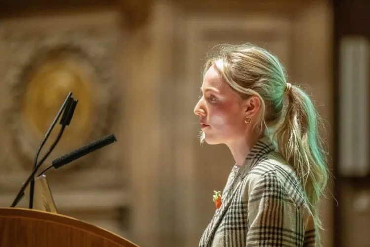 A person stands at a lecturn, speaking