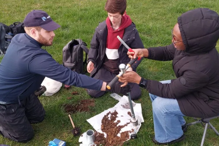 three people examine soil using tools