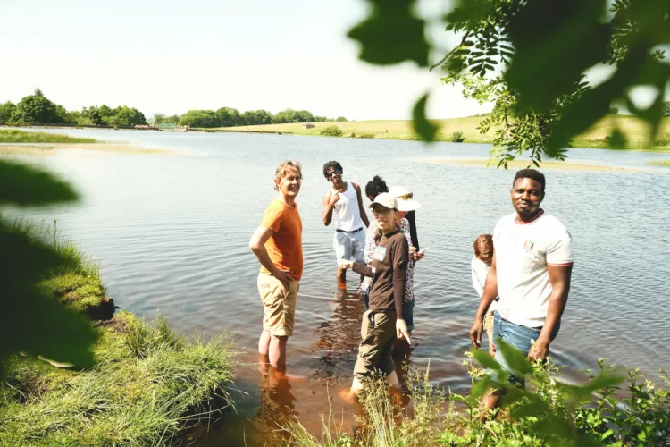 A group of people enjoy standing in water on a sunny day.