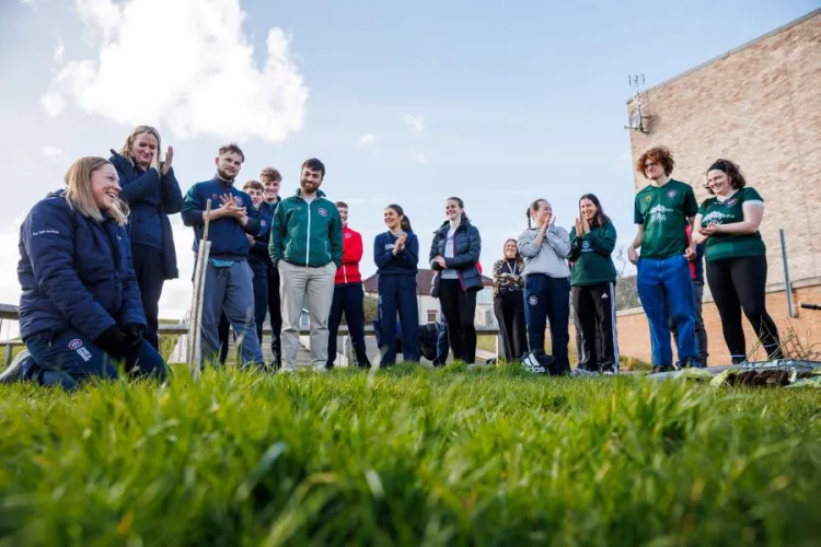 Active Lives' Amanda Marshall demonstrates how to plant a tree to a group of student athletes at Peffermill Playing Fields.