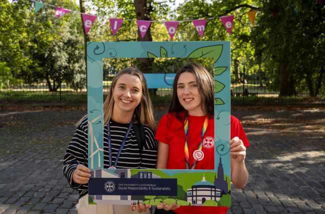 Two women pose with a selfie frame from the University's Department for Social Responsibility and Sustainability, with Welcome W